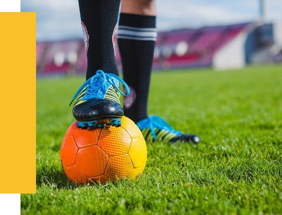 Um close-up da bota de um jogador de futebol sobre a bola, simbolizando treino de futebol, preparação para jogos e desenvolvimento de jogadores.
