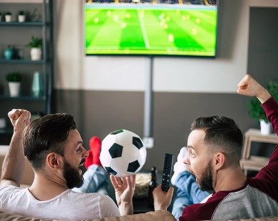 Um grupo de entusiastas do futebol a seguir uma transmissão ao vivo e a reagir a momentos chave do jogo.