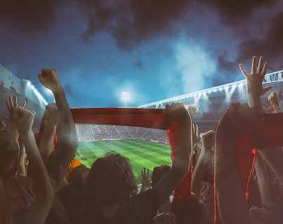 Adeptos apaixonados a levantar cachecóis e a apoiar a sua equipa durante um evento de futebol.