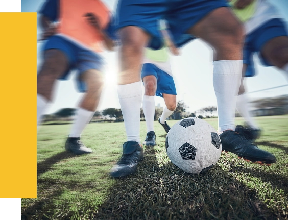 Jogadores de futebol a praticar controlo de bola e trabalho de equipa num campo de relva antes de jogos competitivos.